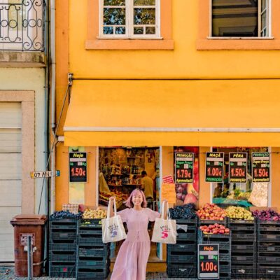 Asian woman, Yishyene Chew, standing in front of grocery shop in Porto, Portugal, with tote bags